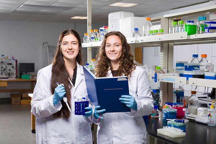 two women in lab coats holding equipment in lab