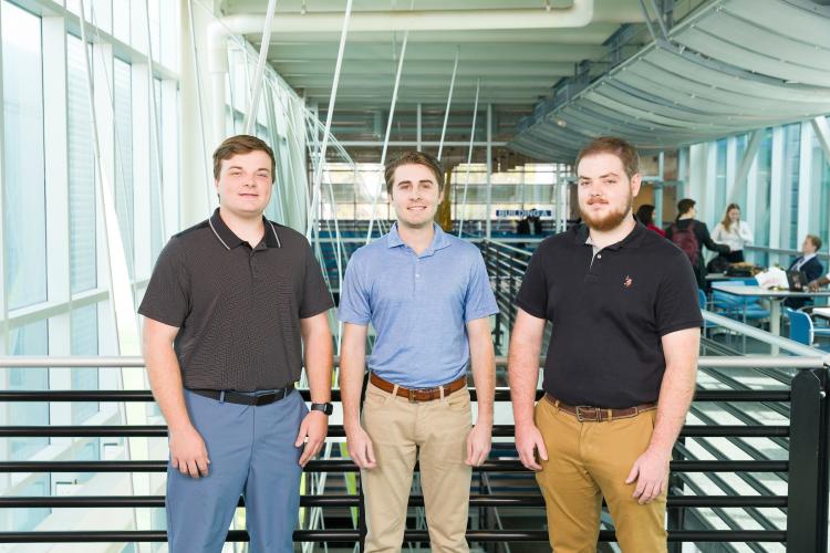 The three members of engineering senior design team 224 stand together on the third floor breezeway at the FAMU-FSU College of Engineering.