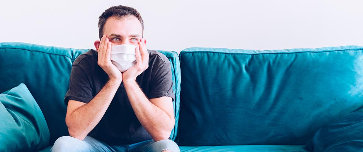 young man with his hands to his chin while wearing a mask