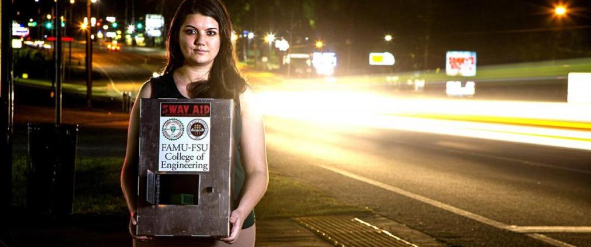 Melanie Munroe stands with her Engineering Senior Design team's human trafficking tracking device prototype