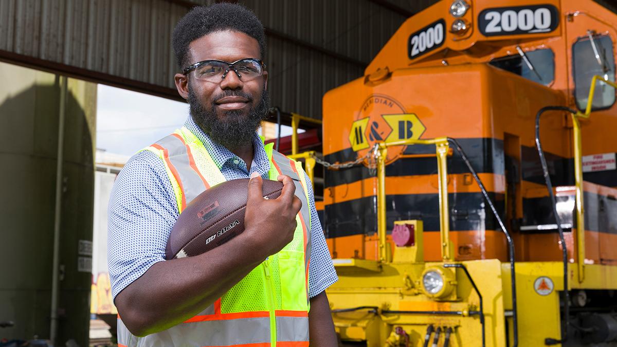 photo of famu-fsu engineering alumni philip sylvester holding football in front of train