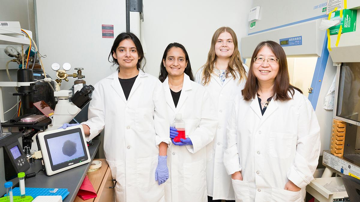 photo of group of females in lab coats standing in lab