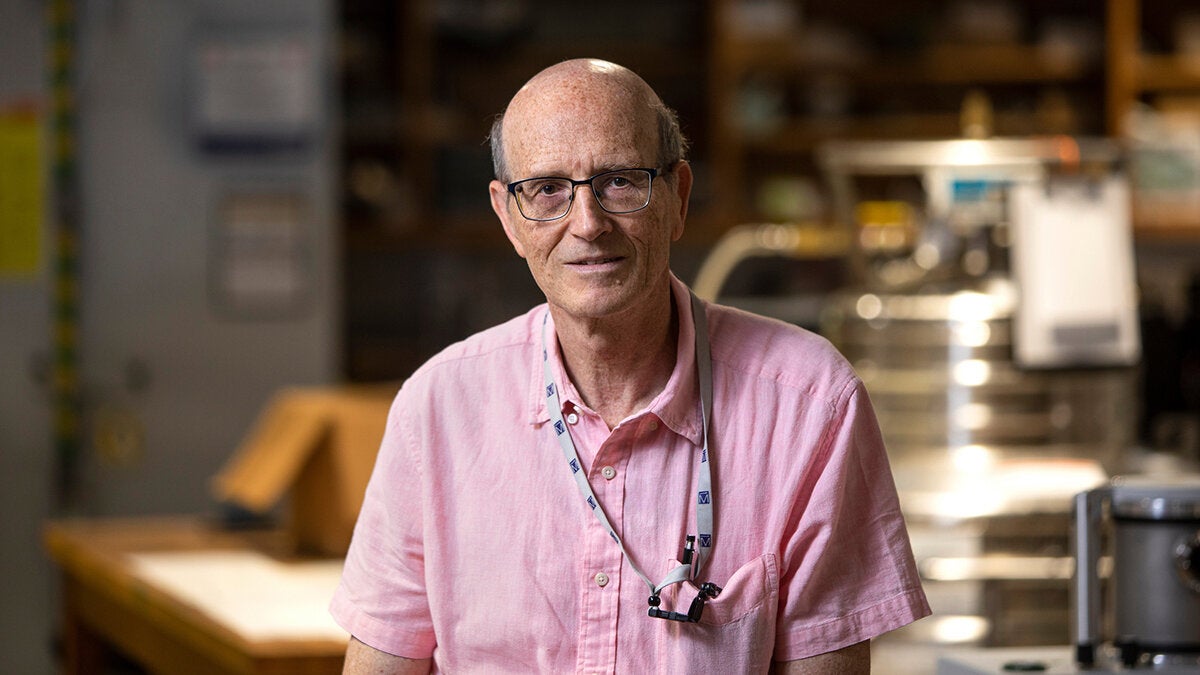 phot of man with glasses and pink button up shirt in lab
