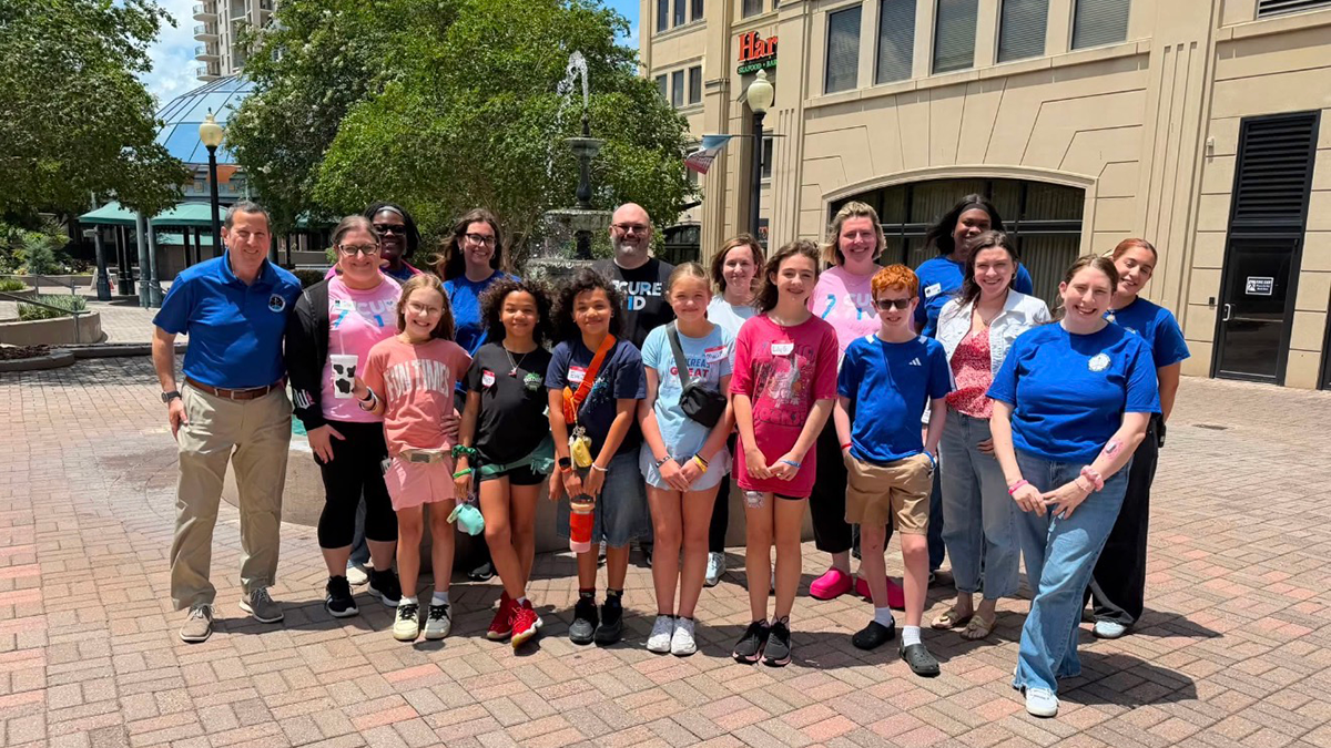 group of kids and adults standing outside a building on a sunny day