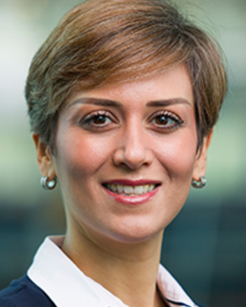smiling woman in white shirt and blue suit with short hair and earrings