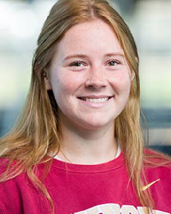 Portrait of a smiling young woman with long blonde hair wearing a red Seminoles sweatshirt against a softly blurred indoor background
