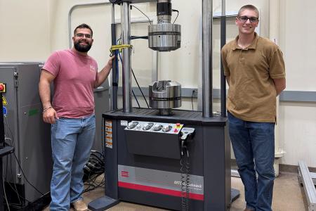 photo of two men standing in front of machine in lab