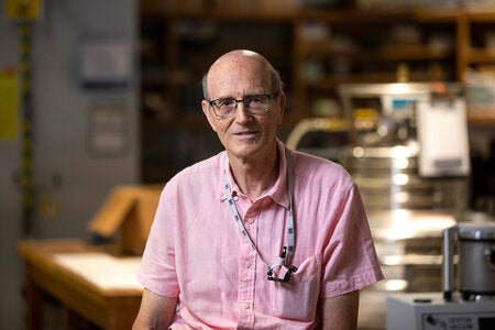 phot of man with glasses and pink button up shirt in lab