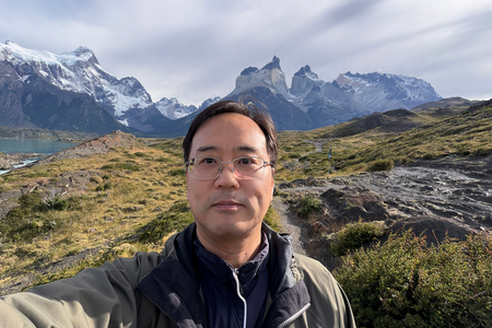 photo of many with glasses in jacket standing in front of chilean mountains and water
