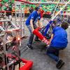 photo of two high school students carrying FRC robot on competition field