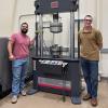 photo of two men standing in front of machine in lab