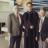 photo of two men and one graduate in robe standing together