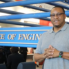 photo of man in glasses and gray polo shirt with hands clasped at chest in the college of engineering