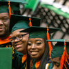 photo of students in green and orange cap and gown at graduation
