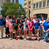 group of kids and adults standing outside a building on a sunny day